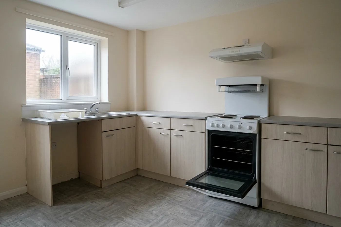 An empty rental kitchen with a freestanding cooker, the oven door open and no belongings on the worktops
